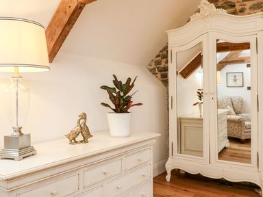 A bedroom with a lamp, plant, and wardrobe at Lake View in Crediton