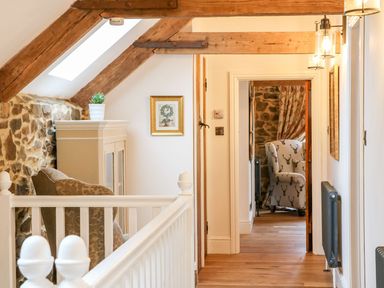 A hallway with a cabinet and an armchair at Lake View in Crediton