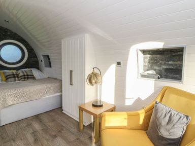 A bedroom with a bed and armchair at Garden Lodge 10 Swansea