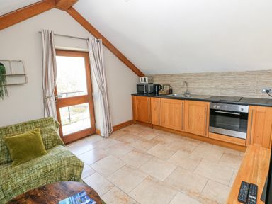 A kitchen with wooden cabinets and appliances at Willow Apartment Oldwalls, Llanrhidian, Gower