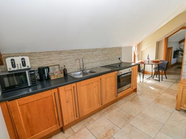 A kitchen with appliances and a dining area at Willow Apartment in Oldwalls, Llanrhidian, Gower