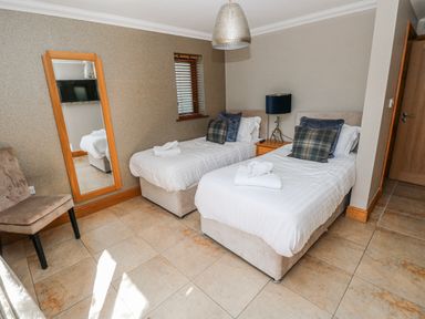 A bedroom with two single beds and a mirror at Ivy Cottage in Oldwalls, Llanrhidian, Gower