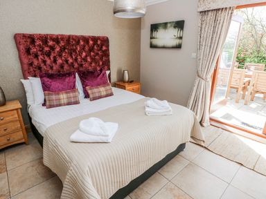 A bedroom with a double bed and a door leading to an outdoor seating area at Ivy Cottage Oldwalls, Llanrhidian, Gower