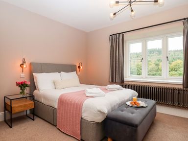 A bedroom with a bed and flowers on a table at Knowle House in Okehampton