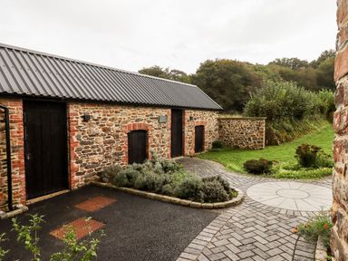 An outdoor area with a stone building and pathway at Knowle House in Okehampton
