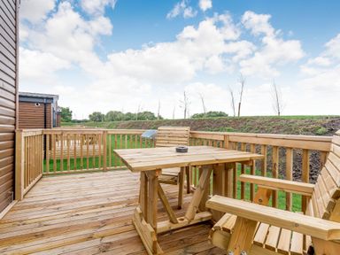 An outdoor space with wooden decking, a table, and chairs at Pear Tree Spa (Pet) Carlton Miniott near Thirsk