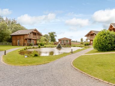 Wooden cabins around a pond at Pear Tree Spa (Pet) Carlton Miniott near Thirsk
