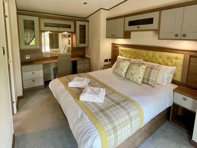 A bedroom with a bed and desk at Acacia Waterside Spa Carlton Miniott near Thirsk