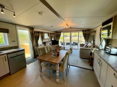 A living room with a dining area and kitchen features at Acacia Waterside Spa Carlton Miniott near Thirsk