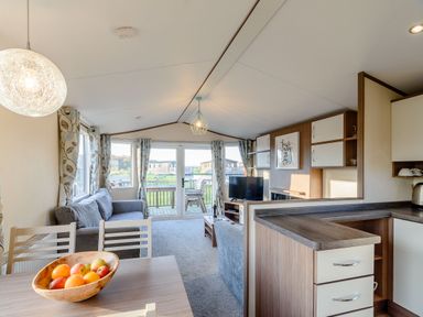 A living room with a sofa and dining area at Alder Waterside Spa in Carlton Miniott near Thirsk