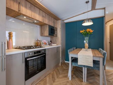A kitchen with a gas stove and dining table at Ellery Waterside Spa in Carlton Miniott near Thirsk