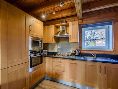A kitchen with wooden cabinets and appliances at Birch Waterside Spa Carlton Miniott near Thirsk