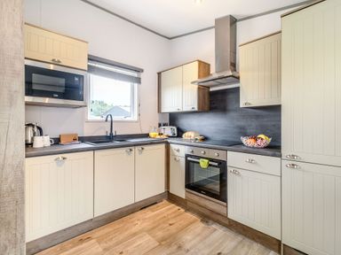 A kitchen with a sink, stove, and microwave at Cedar Spa in Carlton Miniott near Thirsk