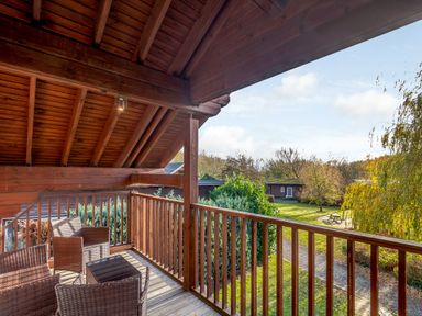 A balcony with outdoor furniture and a view of the garden at Birch Waterside Spa (Pet) Carlton Miniott near Thirsk