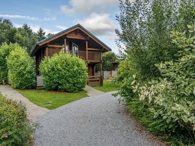A cabin with a balcony surrounded by greenery at Birch Spa (Pet) Carlton Miniott near Thirsk