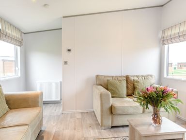 A living room with a sofa, armchair, table, and vase at Cedar Spa (Pet) Carlton Miniott near Thirsk