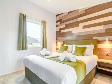 A bedroom with a bed and wooden wall at Cedar Spa (Pet) Carlton Miniott near Thirsk