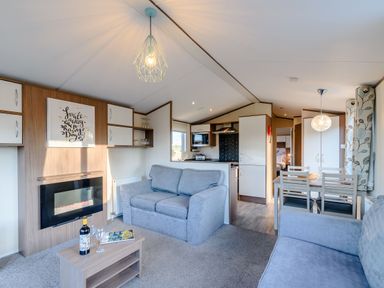 A living room with a sofa and dining area at Alder Waterside Spa (Pet) Carlton Miniott near Thirsk