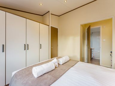 A bedroom with a bed and towels at Oak Waterside Spa Carlton Miniott near Thirsk