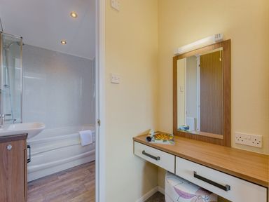 A bathroom with a bathtub and vanity table at Oak Waterside Spa Carlton Miniott near Thirsk