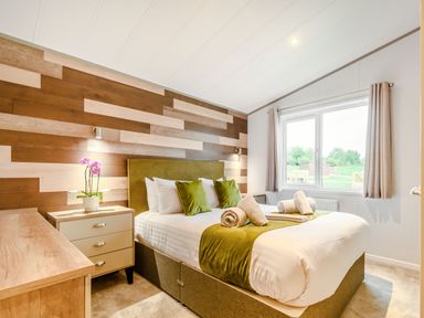 A bedroom with a bed and side table at Oak Waterside Spa Carlton Miniott near Thirsk
