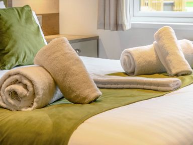 A bed with towels arranged on top at Oak Waterside Spa in Carlton Miniott near Thirsk