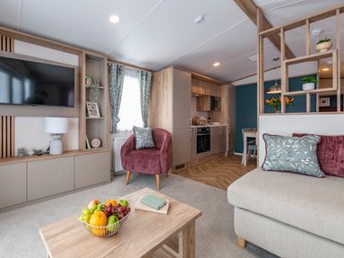 A living room with a kitchen area and a fruit bowl on the table at Redwood Waterside Spa Carlton Miniott near Thirsk