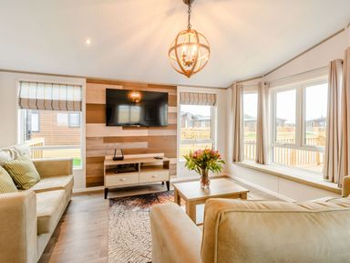 A living room with a television and windows at Spindle Spa in Carlton Miniott near Thirsk