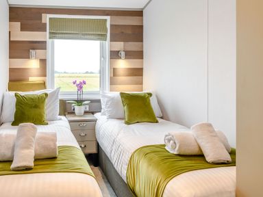 A bedroom with two single beds and a window at Spindle Spa (Pet) Carlton Miniott near Thirsk