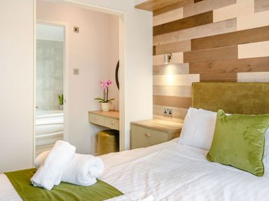 A bedroom with a bed and a view of a bathroom at Spindle Spa (Pet) Carlton Miniott near Thirsk