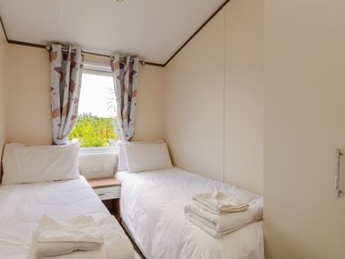A bedroom with twin beds and a window at Oak Waterside Spa (Pet) Carlton Miniott near Thirsk