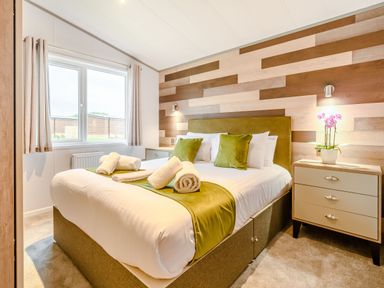 A bedroom with a bed and bedside table at Oak Waterside Spa (Pet) Carlton Miniott near Thirsk