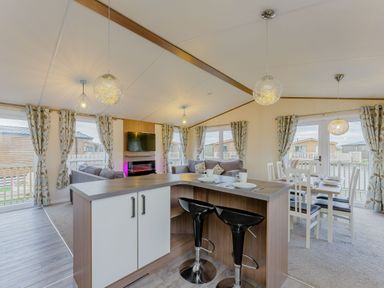 A kitchen island with stools and a dining area at Larch Waterside Spa Carlton Miniott near Thirsk
