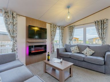 A living room with a television and electric fireplace at Larch Waterside Spa Carlton Miniott near Thirsk