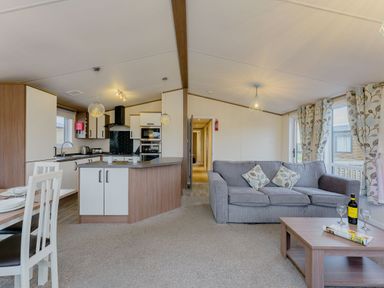 A living room with a sofa and dining area at Larch Waterside Spa Carlton Miniott near Thirsk