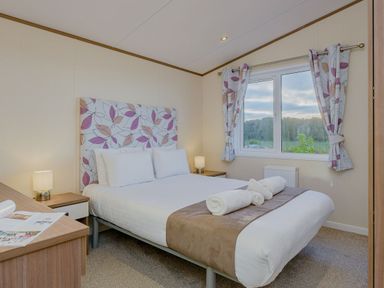 A bedroom with a double bed and nightstand at Larch Waterside Spa Carlton Miniott near Thirsk