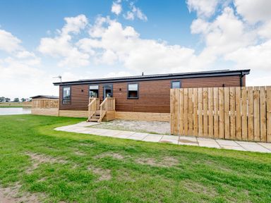 A wooden cabin with steps and a fenced area at Beech Waterside Spa Carlton Miniott near Thirsk