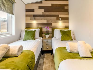 A bedroom with twin beds and a bedside table at Beech Waterside Spa Carlton Miniott near Thirsk