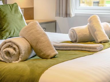 A bed with rolled towels and a cushion at Beech Waterside Spa Carlton Miniott near Thirsk