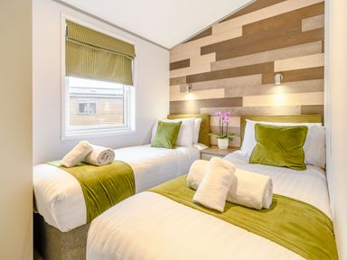 A bedroom with two beds and a plant at Beech Waterside Spa (Pet) Carlton Miniott near Thirsk