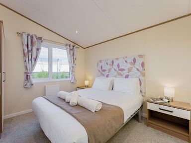 A bedroom with a bed and bedside table at Larch Waterside Spa (Pet) Carlton Miniott near Thirsk