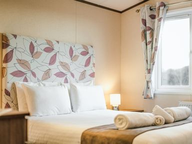A bedroom with a bed and lamp at Larch Waterside Spa (Pet) Carlton Miniott near Thirsk