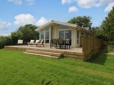An outdoor area with a lodge and seating at Plas Marchog Lodge, Rhoscefnhir near Pentraeth
