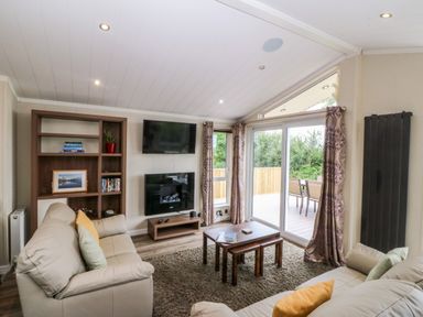 A living room with a sofa and television at Plas Marchog Lodge Rhoscefnhir near Pentraeth