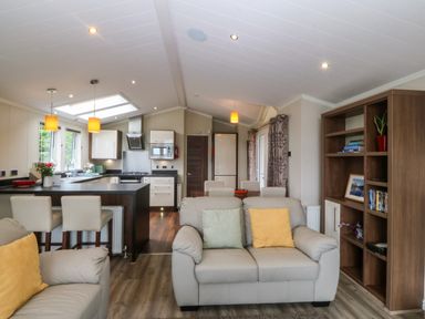A living room with sofa and kitchen island at Plas Marchog Lodge Rhoscefnhir near Pentraeth