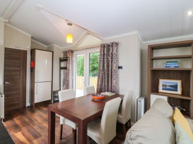 A dining room with a table and chairs at Plas Marchog Lodge near Rhoscefnhir