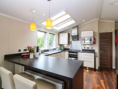 A kitchen with appliances and a kitchen island at Plas Marchog Lodge Rhoscefnhir near Pentraeth