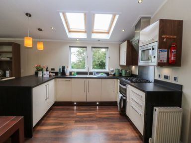A kitchen with counter, sink, and stove at Plas Marchog Lodge Rhoscefnhir near Pentraeth