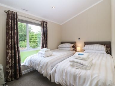A bedroom with two beds and a window at Plas Marchog Lodge Rhoscefnhir near Pentraeth