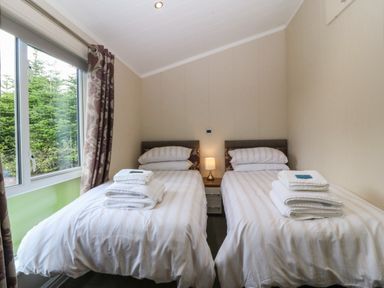 A bedroom with twin beds and a lamp at Plas Marchog Lodge Rhoscefnhir near Pentraeth
